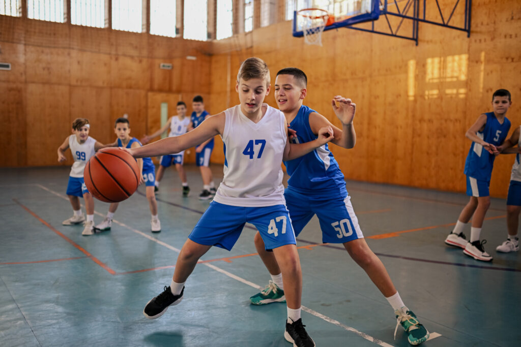 Basketball players in a scrimmage practicing no-go drills, enhancing decision-making, control, and defensive skills on the court.