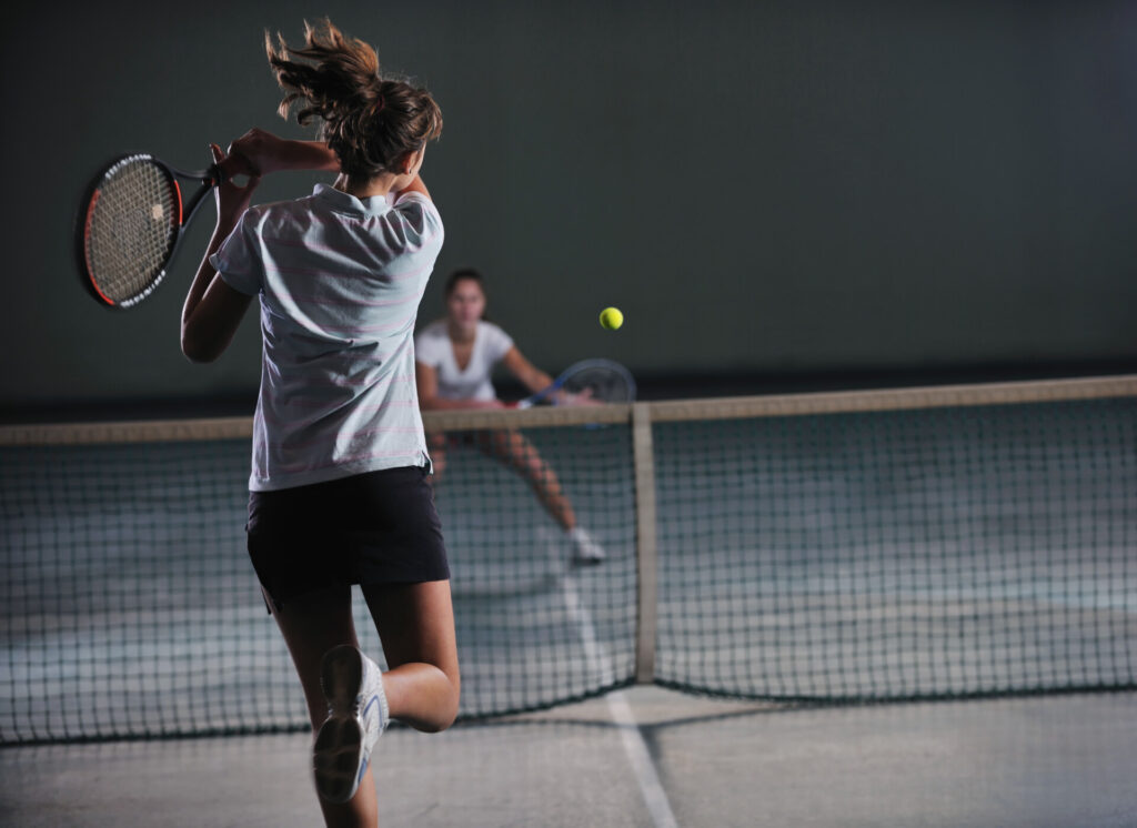 young girls playing tennis game indoor in tennis court